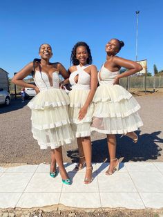 three women standing next to each other in dresses