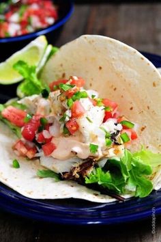 two tacos with lettuce, tomatoes and other toppings on a blue plate