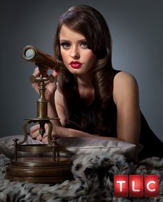 a woman is looking through a telescope with her hand on the top of it, while laying down