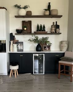 a kitchen with black and white cabinets, open shelvings, potted plants on top of the shelves