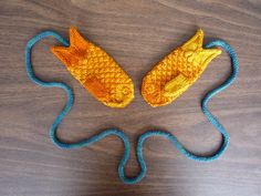 two knitted fish shaped objects sitting on top of a wooden table