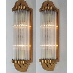 two wall lights that are next to each other on a white wall with gold trimmings