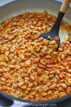 the beans are being stirred with a spatula to stir them in some type of sauce