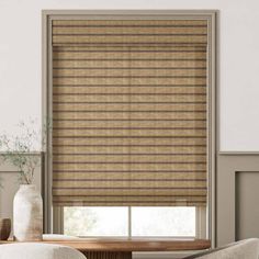 a living room with a large window covered in bamboo blinds and a chair next to it