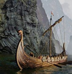 an old boat with many people on it in the water next to a mountain range