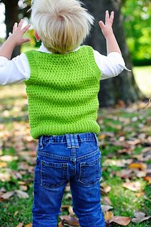 a little boy standing in the grass with his hands up and looking at leaves on the ground