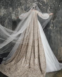 a woman in a wedding dress with veils on her head and hands behind her back