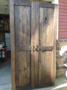 an old wooden door in front of a red building with a toilet on the sidewalk