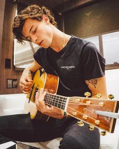 a young man playing an acoustic guitar in his living room