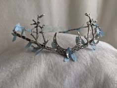 This gorgeous tiara features a filigree crescent moon, a sparkling opalescent blue crystal in the center, and branches on either side. Fallen sky blue leaves surround the flexible branch-like base. This piece is adjustable with a ribbon tie in the back. Choose between a silver moon and branches as pictured or bronze! Woodland Tiara, Magical Jewelry, Coron, Head Piece, Dessin Adorable, Fantasy Dress, Fancy Jewelry, Fantasy Jewelry, Tiaras And Crowns