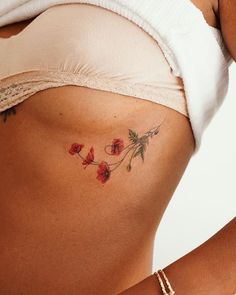 a close up of a woman's stomach with red flowers on the side and behind her