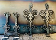 four wrought iron doors on the side of a building with blue and green paint behind them