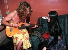 a man playing guitar next to a woman sitting on a couch