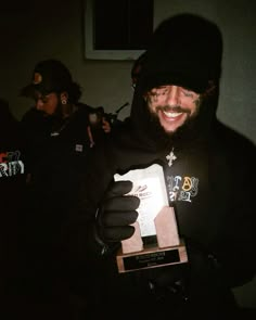 a man in black hoodie holding up a box