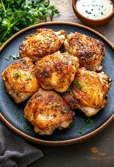 some chicken is on a plate with sauce and parsley in the bowl next to it