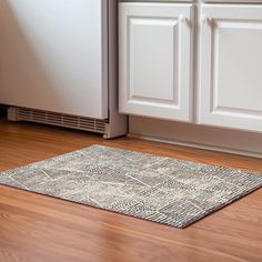 a kitchen with wooden floors and white cupboards next to a dishwasher on the floor