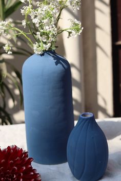 two blue vases sitting on top of a table next to white and red flowers