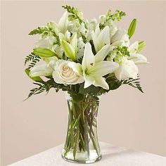 a vase filled with white flowers sitting on top of a table next to a cup and saucer