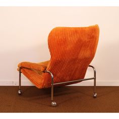 an orange chair sitting on top of a brown carpeted floor next to a white wall