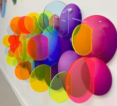 a colorful wall hanging on the side of a white wall with lots of different colored circles