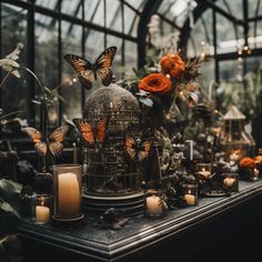 a table topped with lots of candles next to a birdcage filled with flowers