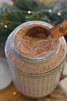 a glass jar filled with brown powder next to a christmas tree