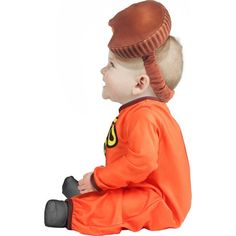 a small child sitting on the ground wearing an orange outfit and a brown hat with horns