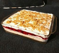 a cake with white frosting and crumbled toppings in a glass dish