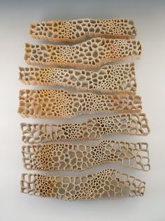 four pieces of wood with holes in them on a white surface and one piece is cut out to look like corals