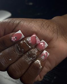 a woman's hand with pink and white flowers on it, holding onto her nails