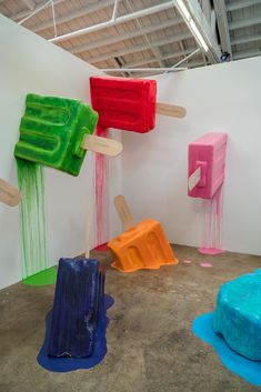 an art exhibit with colorful sculptures on the wall and paint splattered over them