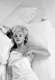 black and white photograph of marilyn monroe laying in bed with her head on the pillow