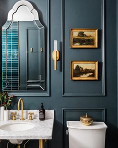 a white toilet sitting next to a bathroom sink under a mirror on top of a wall