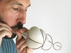 a man is blowing on an object with his mouth and nose to the side while holding it in one hand