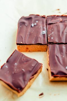 four pieces of chocolate frosted brownies sitting on top of a white tablecloth