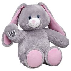 a purple stuffed animal with pink ears and paws on it's chest, sitting up against a white background