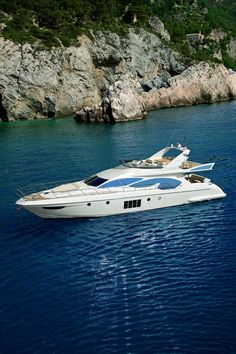 a large white boat floating on top of a body of water next to a rocky shore