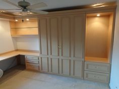 an empty room with built - in closets and drawers on the wall, along with a ceiling fan