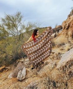 a woman is holding a blanket in the desert