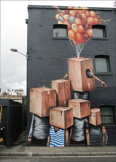 a large painting on the side of a building with many boxes in front of it