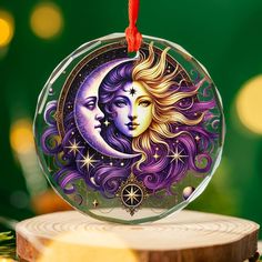 a glass ornament with an image of the moon and two faces on it