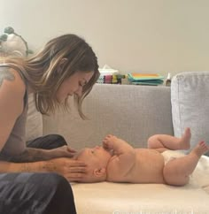 a woman is playing with her baby on the couch