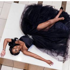 a woman laying on top of a table wearing a black dress and high heeled shoes