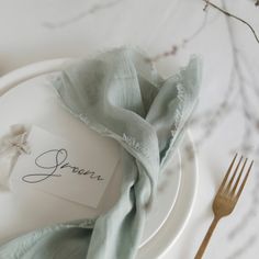 a place setting with napkins, silverware and a name tag on the plate