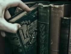 a person holding an open book in front of some books