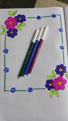 two pens sitting on top of an open notebook with flowers drawn on the pages behind them