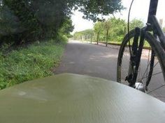 a bicycle parked on the side of a road next to a tree and grass covered field