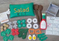 the contents of a salad kit laid out on a wooden table with utensils