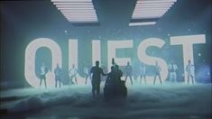 a group of people standing in front of a sign that says quest on the wall