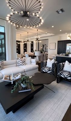 a living room filled with furniture and a chandelier hanging from the ceiling above it